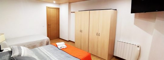 Habitación con cama de matrimonio color gris y naranja.